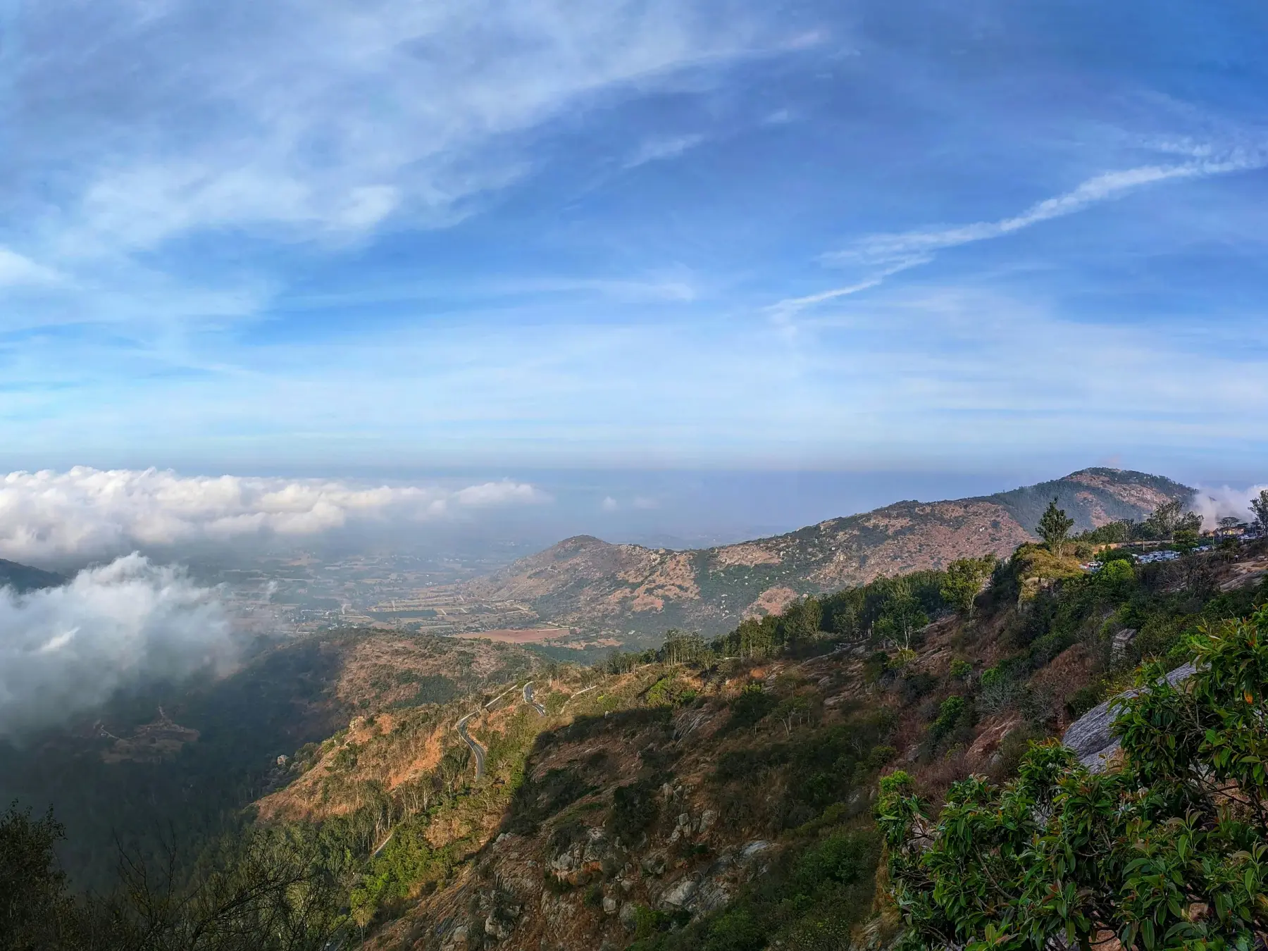Panoramic view of the Nandi Hills range with clouds rolling across the valleys