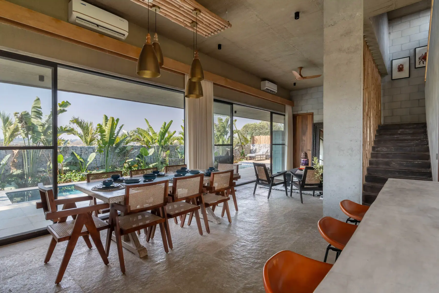 Open dining room at Villa Maaya with brass pendants and cane chairs